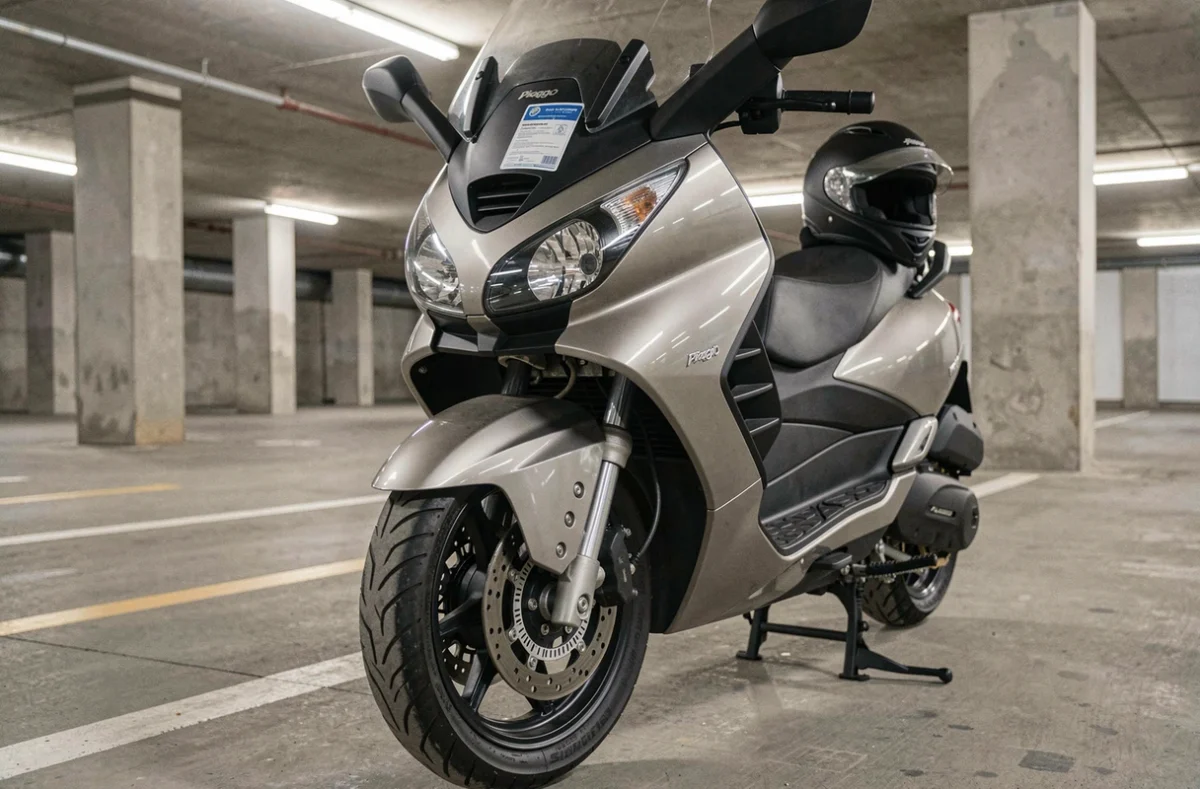 Détail des roues avant d'un scooter trois roues MP3 350 avec vignette d'assurance sur le pare-brise